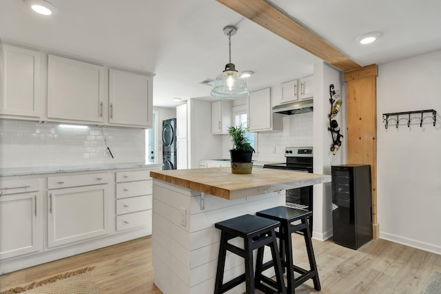 kitchen featuring stacked washer / dryer, white cabinets, a center island, wood counters, and light hardwood / wood-style flooring