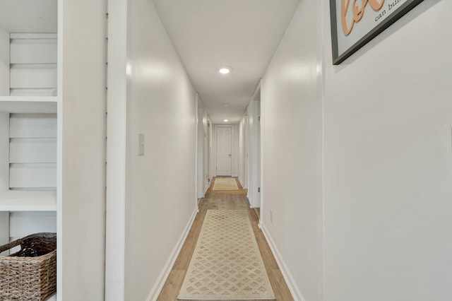 hall featuring built in shelves and light hardwood / wood-style flooring