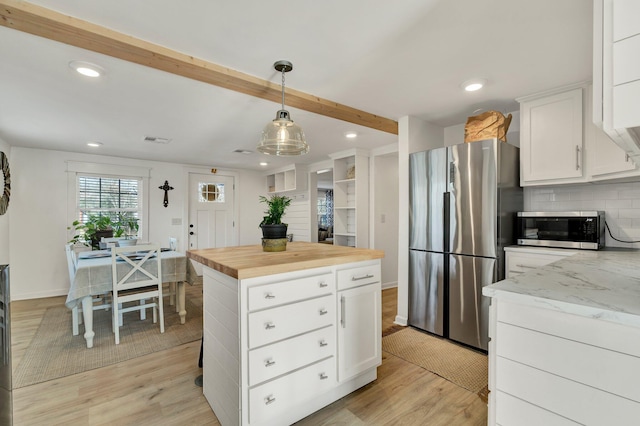 kitchen with butcher block counters, appliances with stainless steel finishes, light wood-type flooring, white cabinets, and a center island