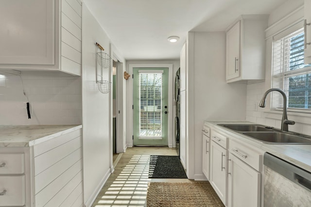 kitchen featuring plenty of natural light, tasteful backsplash, stainless steel dishwasher, white cabinets, and sink