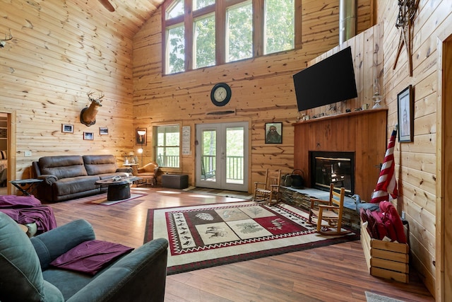 living area with high vaulted ceiling, wood walls, and a healthy amount of sunlight