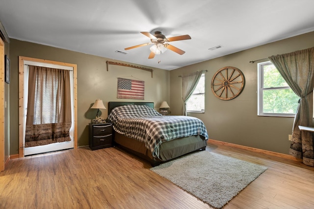 bedroom featuring ceiling fan, baseboards, visible vents, and wood finished floors