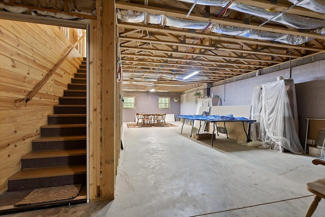 basement featuring concrete block wall and stairway