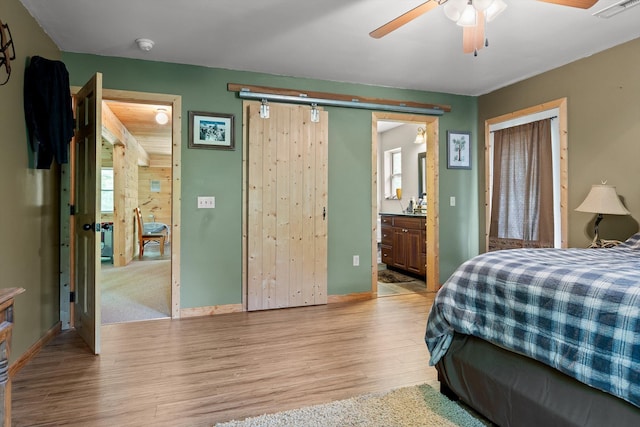 bedroom featuring baseboards, visible vents, light wood finished floors, and ensuite bath