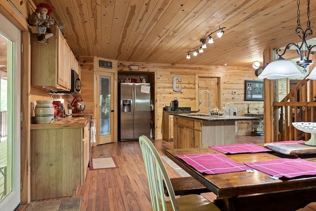 dining space with track lighting, light wood finished floors, wooden walls, and wooden ceiling