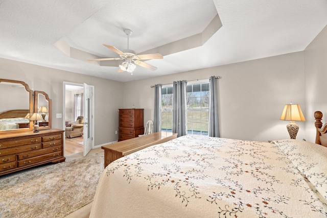 bedroom featuring ceiling fan, light carpet, and a raised ceiling