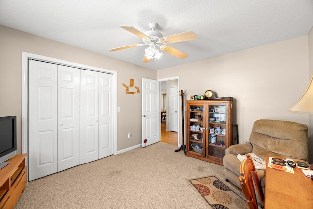 sitting room with ceiling fan, light colored carpet, and a textured ceiling