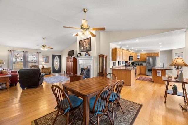 dining space featuring light wood-type flooring, vaulted ceiling, sink, and ceiling fan