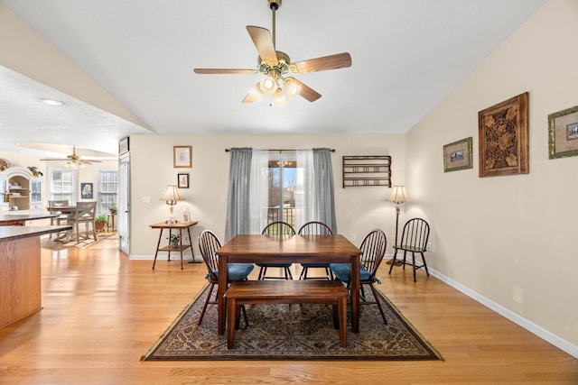 dining room featuring light wood-type flooring, vaulted ceiling, and ceiling fan