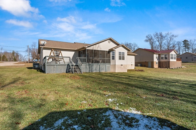 back of property featuring a wooden deck, a yard, and a sunroom