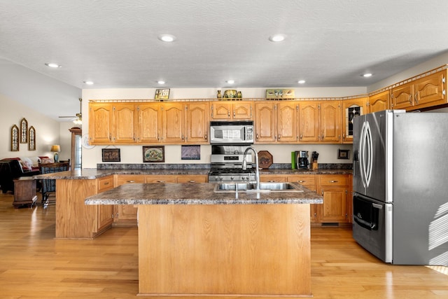 kitchen featuring light hardwood / wood-style floors, a center island with sink, sink, a breakfast bar area, and stainless steel appliances