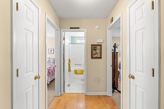 hallway featuring a textured ceiling and light hardwood / wood-style flooring