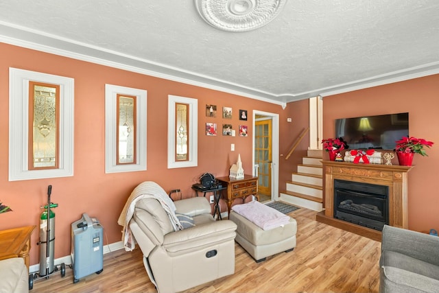 living room with a textured ceiling, light hardwood / wood-style flooring, and ornamental molding