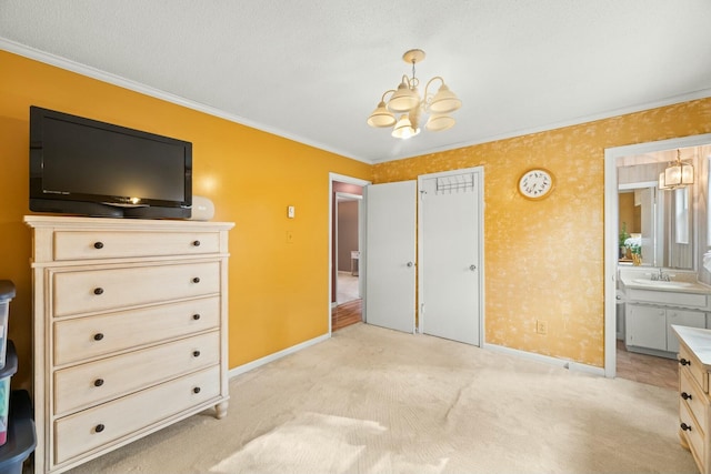 carpeted bedroom featuring ensuite bath, ornamental molding, a textured ceiling, sink, and a chandelier