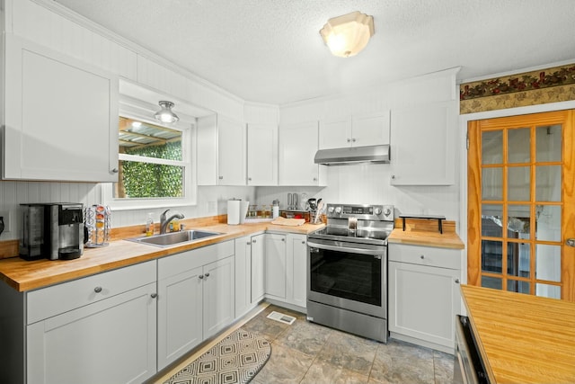 kitchen with butcher block countertops, sink, a textured ceiling, and stainless steel electric range