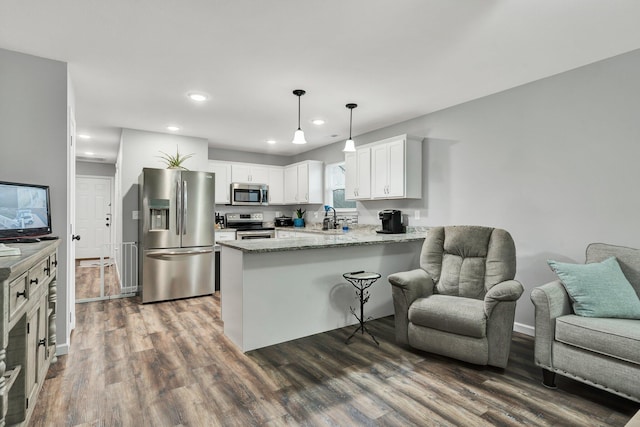 kitchen with sink, stainless steel appliances, white cabinets, decorative light fixtures, and kitchen peninsula