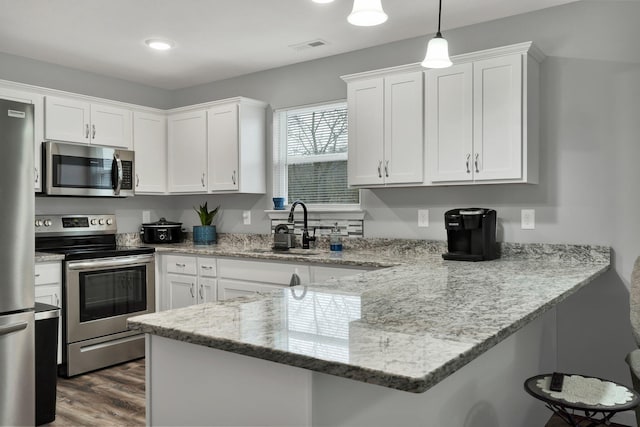 kitchen featuring white cabinetry, appliances with stainless steel finishes, pendant lighting, and kitchen peninsula