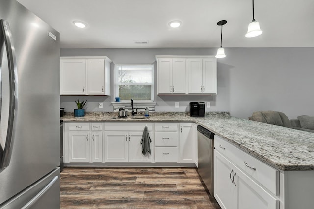 kitchen featuring sink, white cabinetry, decorative light fixtures, appliances with stainless steel finishes, and kitchen peninsula