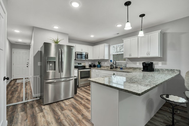 kitchen featuring white cabinetry, stone countertops, decorative light fixtures, dark hardwood / wood-style floors, and stainless steel appliances