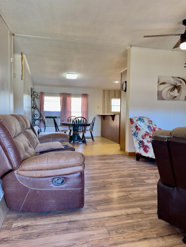 living room featuring ceiling fan, hardwood / wood-style floors, and a textured ceiling