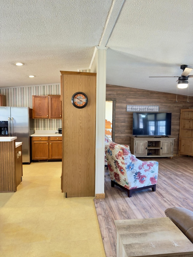 living room with ceiling fan, wooden walls, and a textured ceiling