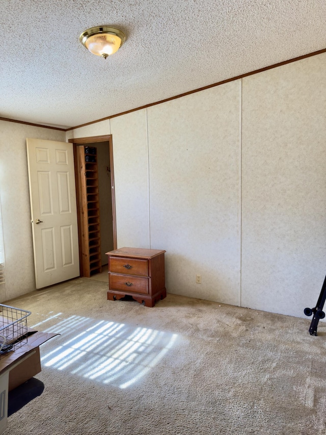 unfurnished bedroom with light carpet, crown molding, a closet, and a textured ceiling