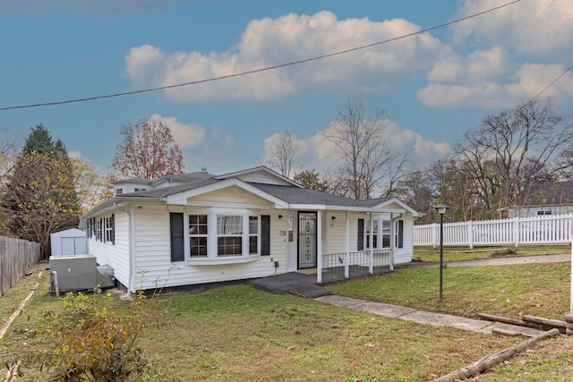 bungalow with a front yard, a porch, and a storage shed