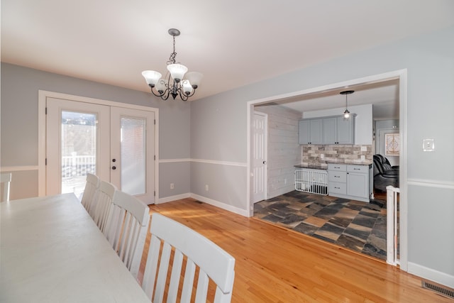 dining space featuring wood-type flooring, an inviting chandelier, and french doors