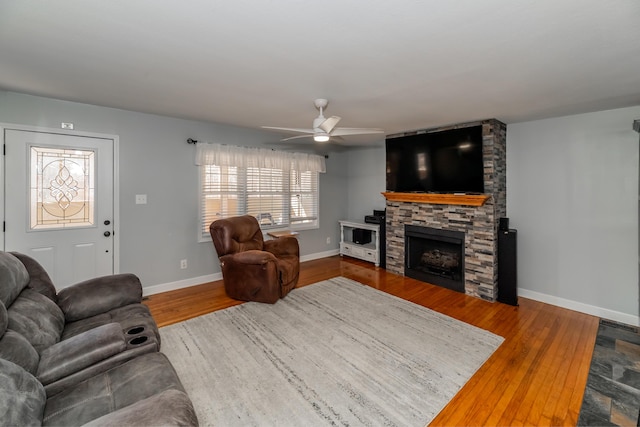 living room with wood-type flooring, ceiling fan, and a fireplace