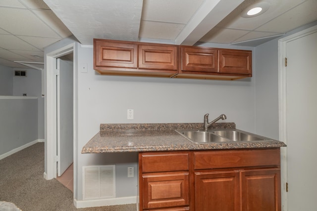 kitchen with a paneled ceiling, sink, and light colored carpet