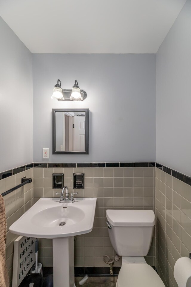 bathroom featuring toilet, sink, and tile walls