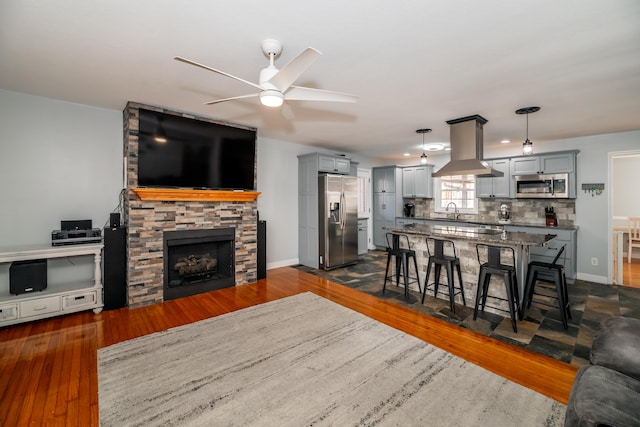 living room featuring ceiling fan, dark hardwood / wood-style floors, sink, and a fireplace