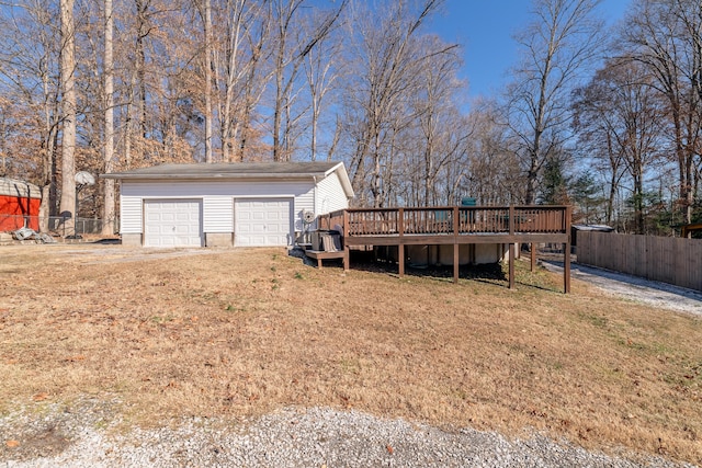 exterior space featuring a garage, an outdoor structure, a lawn, and a deck