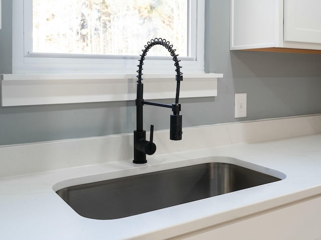 interior details with white cabinetry and sink