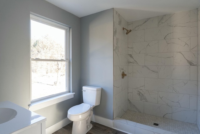 bathroom with toilet, hardwood / wood-style floors, vanity, and a tile shower