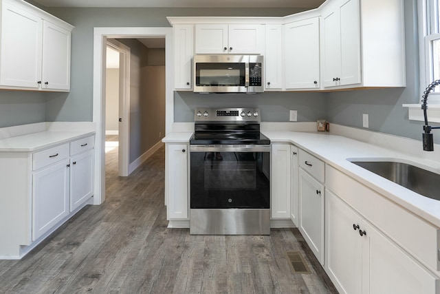 kitchen featuring white cabinets, appliances with stainless steel finishes, dark hardwood / wood-style floors, and sink