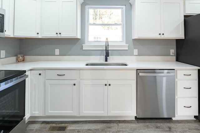 kitchen featuring dark hardwood / wood-style flooring, white cabinetry, sink, and stainless steel appliances