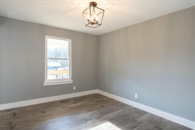 spare room featuring hardwood / wood-style floors and a notable chandelier