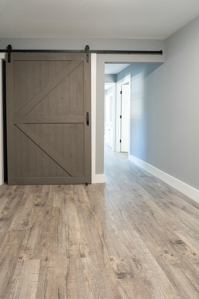 spare room featuring a barn door and light hardwood / wood-style floors