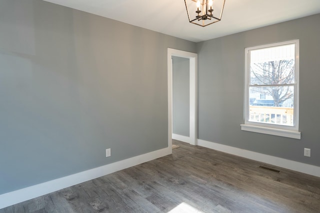 unfurnished room with wood-type flooring and a notable chandelier