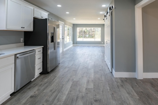 kitchen featuring a barn door, white cabinetry, stainless steel appliances, and light wood-type flooring