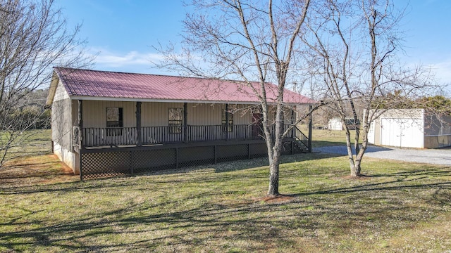 view of front facade featuring an outbuilding, a storage unit, a porch, a front yard, and metal roof