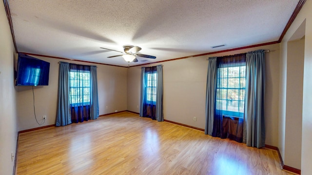 empty room featuring ceiling fan, plenty of natural light, a textured ceiling, and hardwood / wood-style flooring