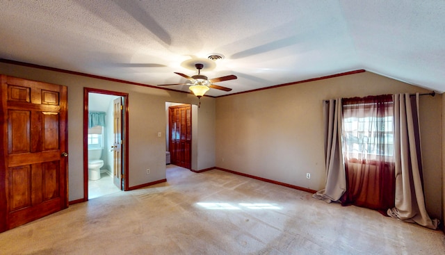 unfurnished bedroom featuring ceiling fan, ensuite bathroom, lofted ceiling, a textured ceiling, and light carpet