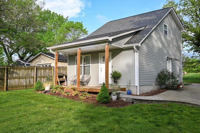 rear view of house featuring covered porch and a lawn