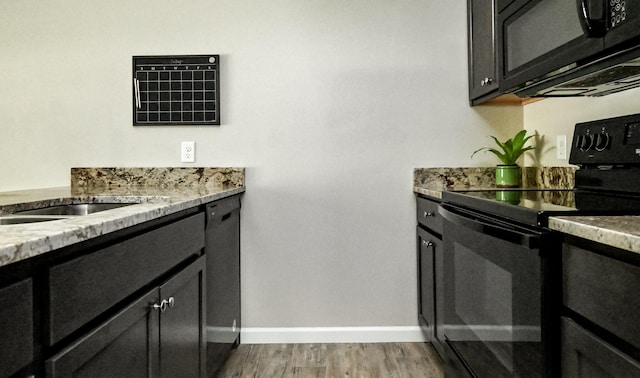 kitchen featuring light stone counters, black appliances, and light wood-type flooring