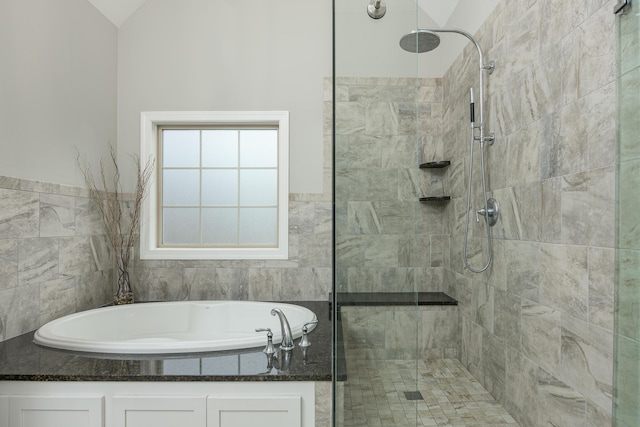 bathroom with tile walls, vaulted ceiling, and plus walk in shower