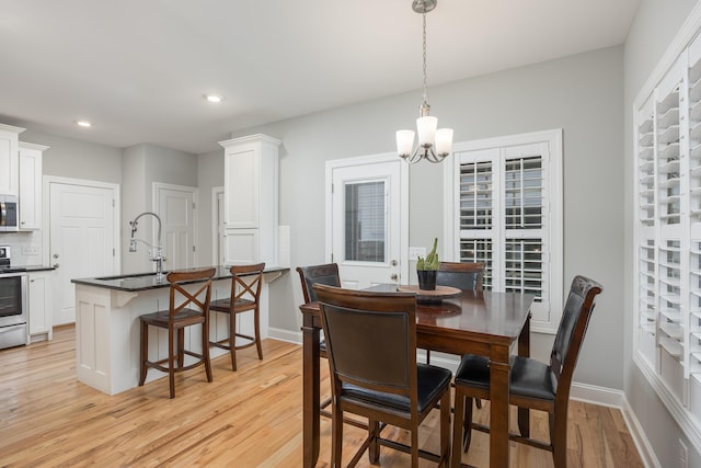 dining space featuring sink, a notable chandelier, and light wood-type flooring