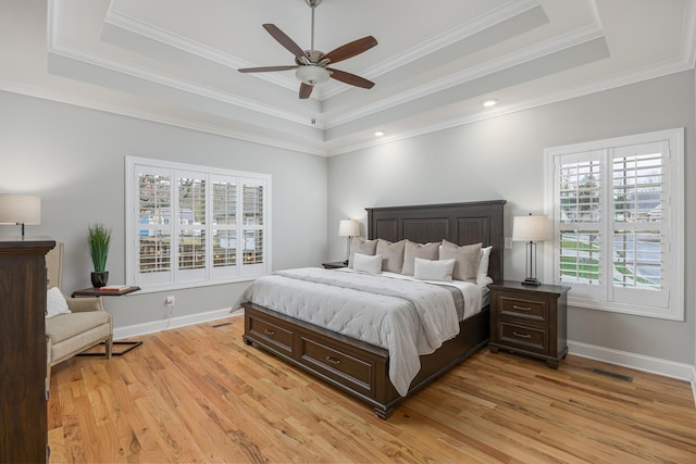 bedroom featuring ceiling fan, multiple windows, ornamental molding, and a raised ceiling