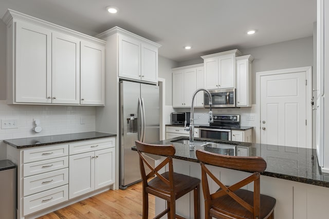 kitchen featuring a breakfast bar, backsplash, white cabinets, and stainless steel appliances